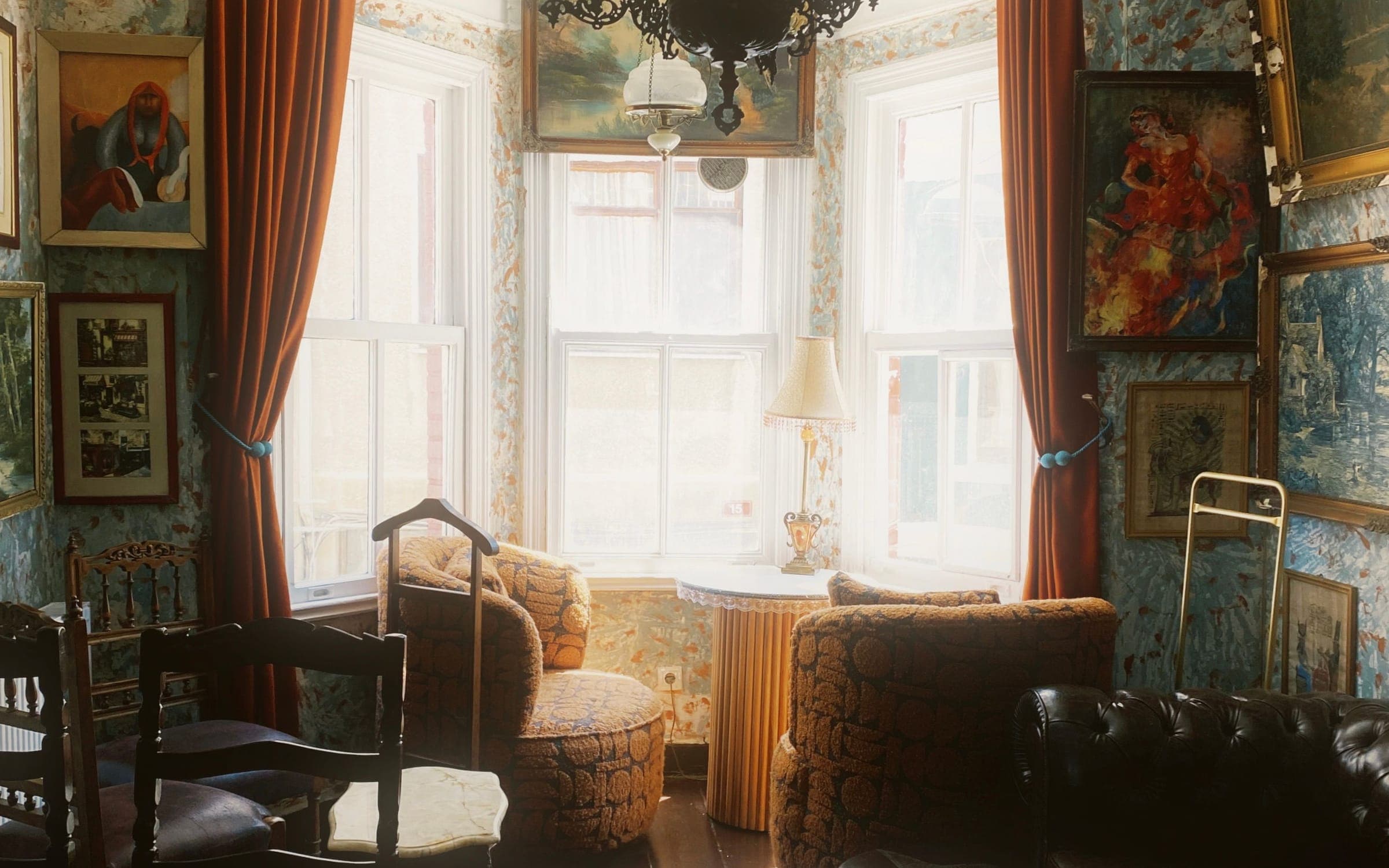 A lived-in bay-window living room with armchairs and afternoon light
